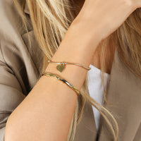 A silver bracelet with a beaded design and a heart-shaped charm, engraved with initials and a date 