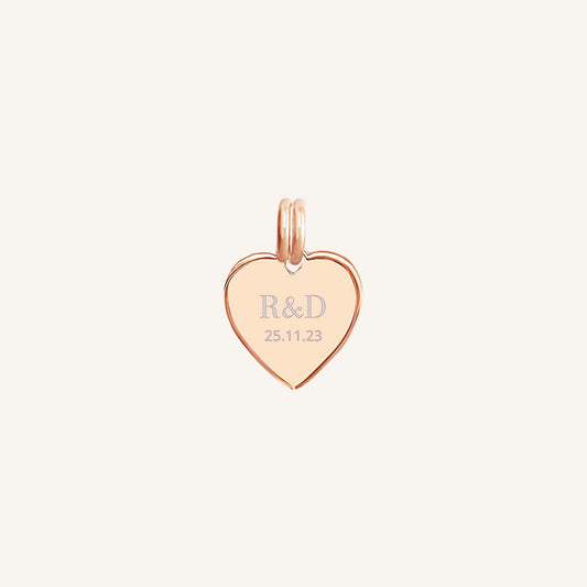 A rose heart-shaped charm with engraved initials and a date
