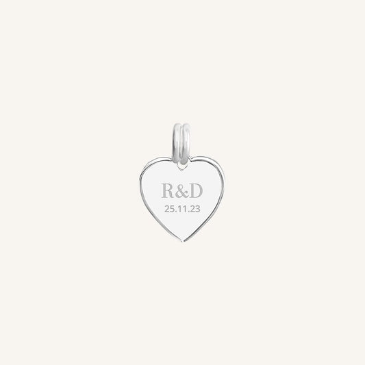A silver heart-shaped charm with engraved initials and a date