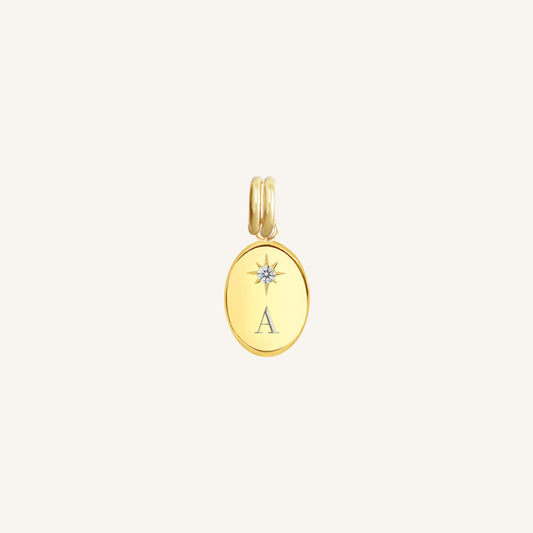 Gold pendant with 'A' initial on a light beige background