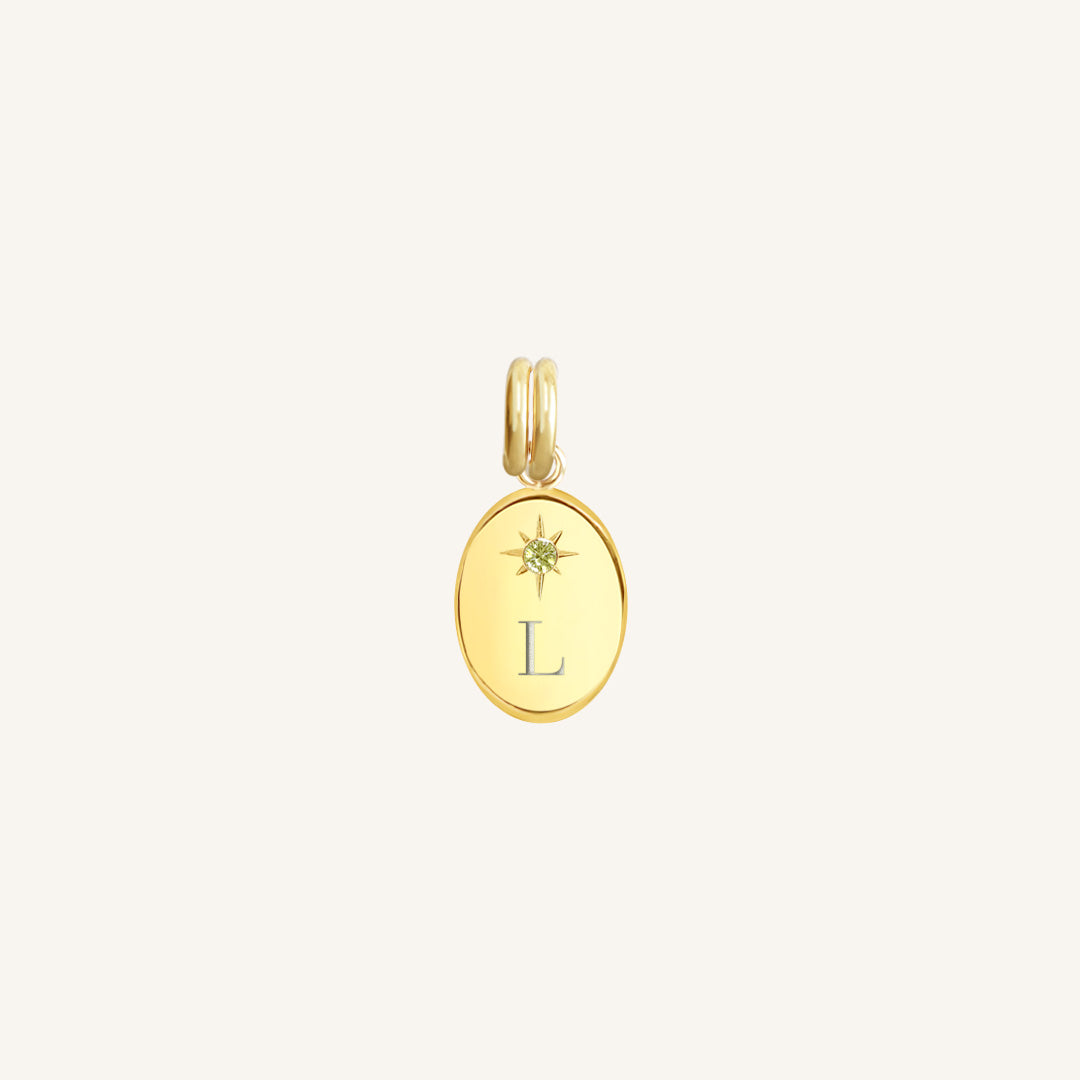 Gold pendant with letter 'L' on a light beige background