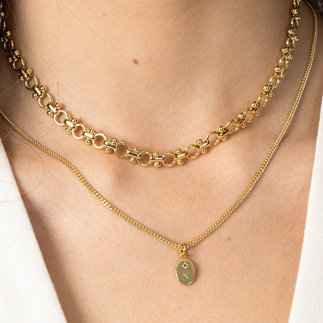 Two gold necklaces on a person's neck with a close-up view.
