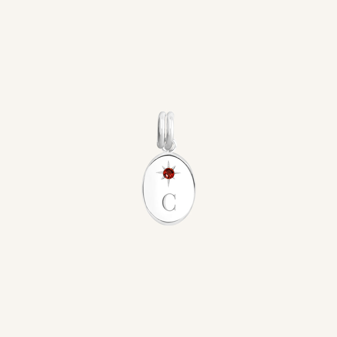 Silver pendant with a red gemstone and letter 'C' on a white background