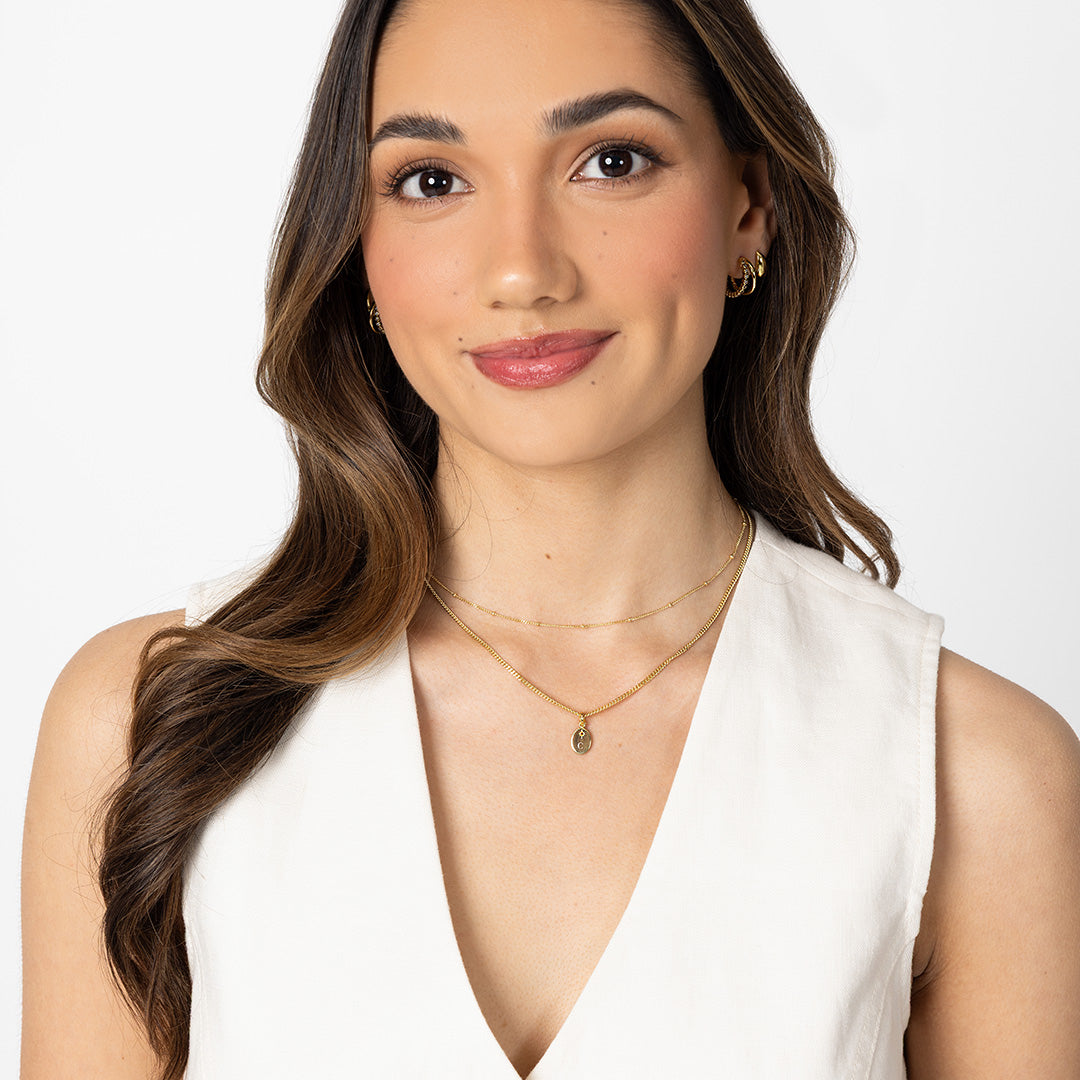Woman wearing a white sleeveless top and gold jewelry on a white background