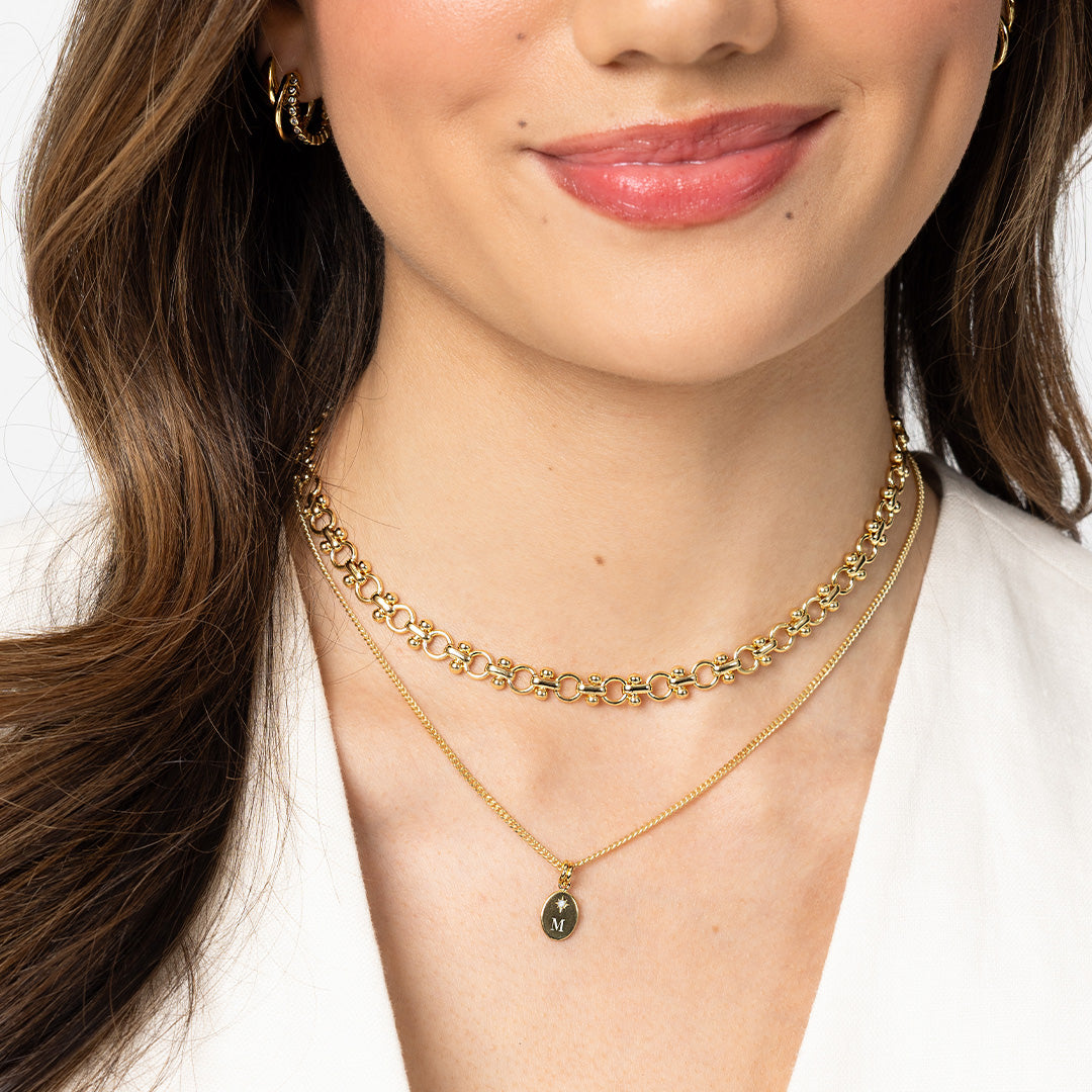 Close-up of a woman wearing a gold necklace with a pendant on a white background