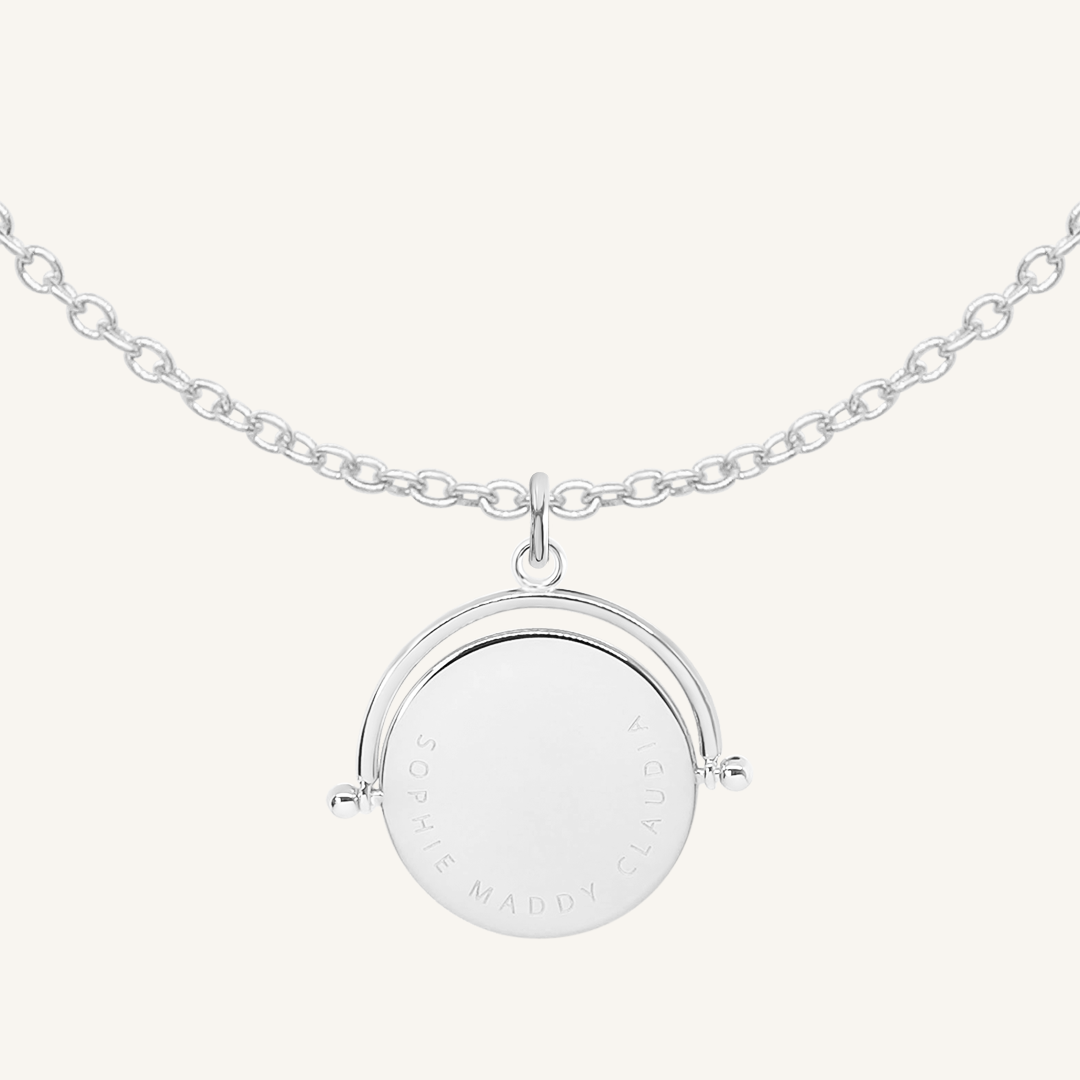 A silver-coloured, engraved pendant with, featuring a spinning mechanism, on chain