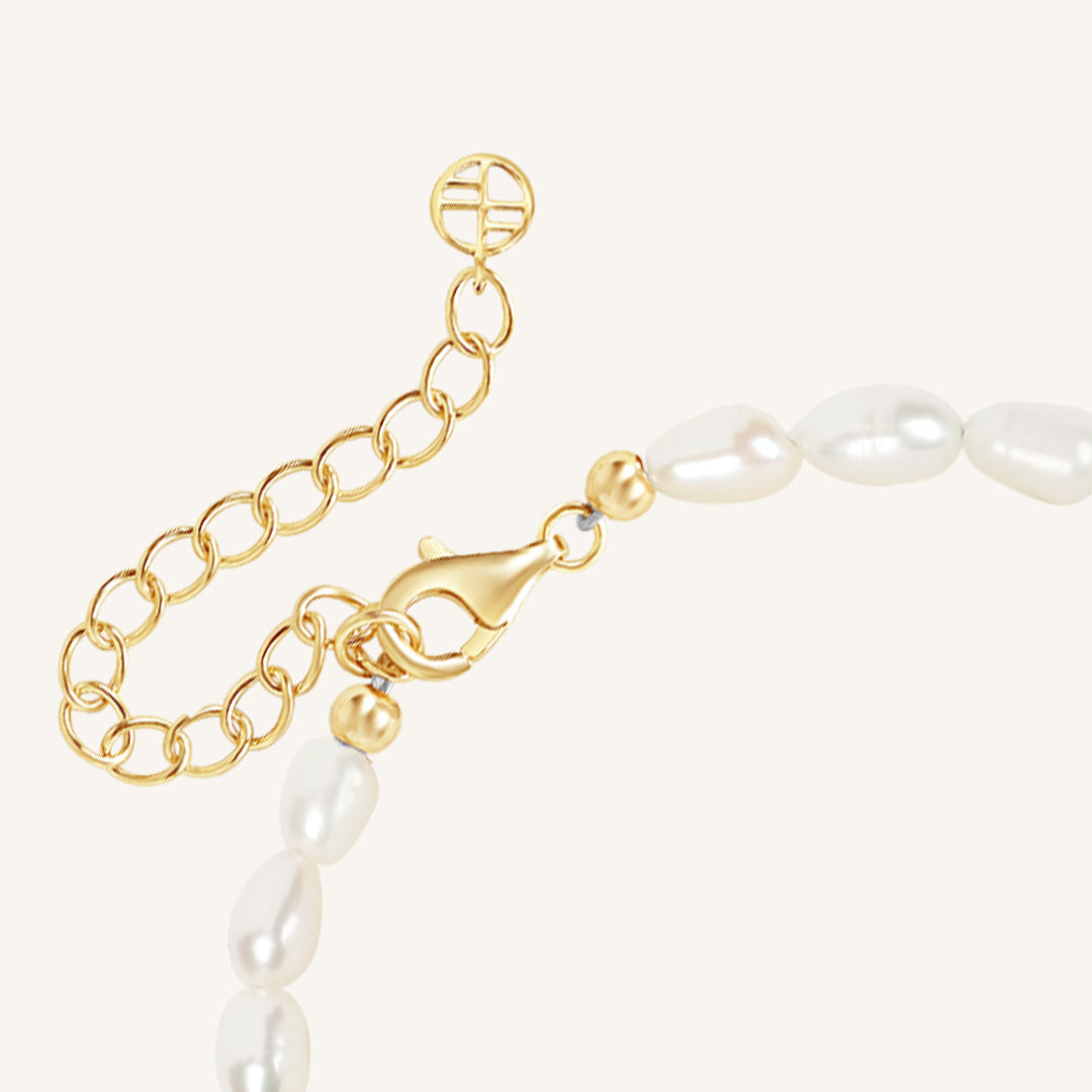 Gold chain and pearl bracelet on a white background
