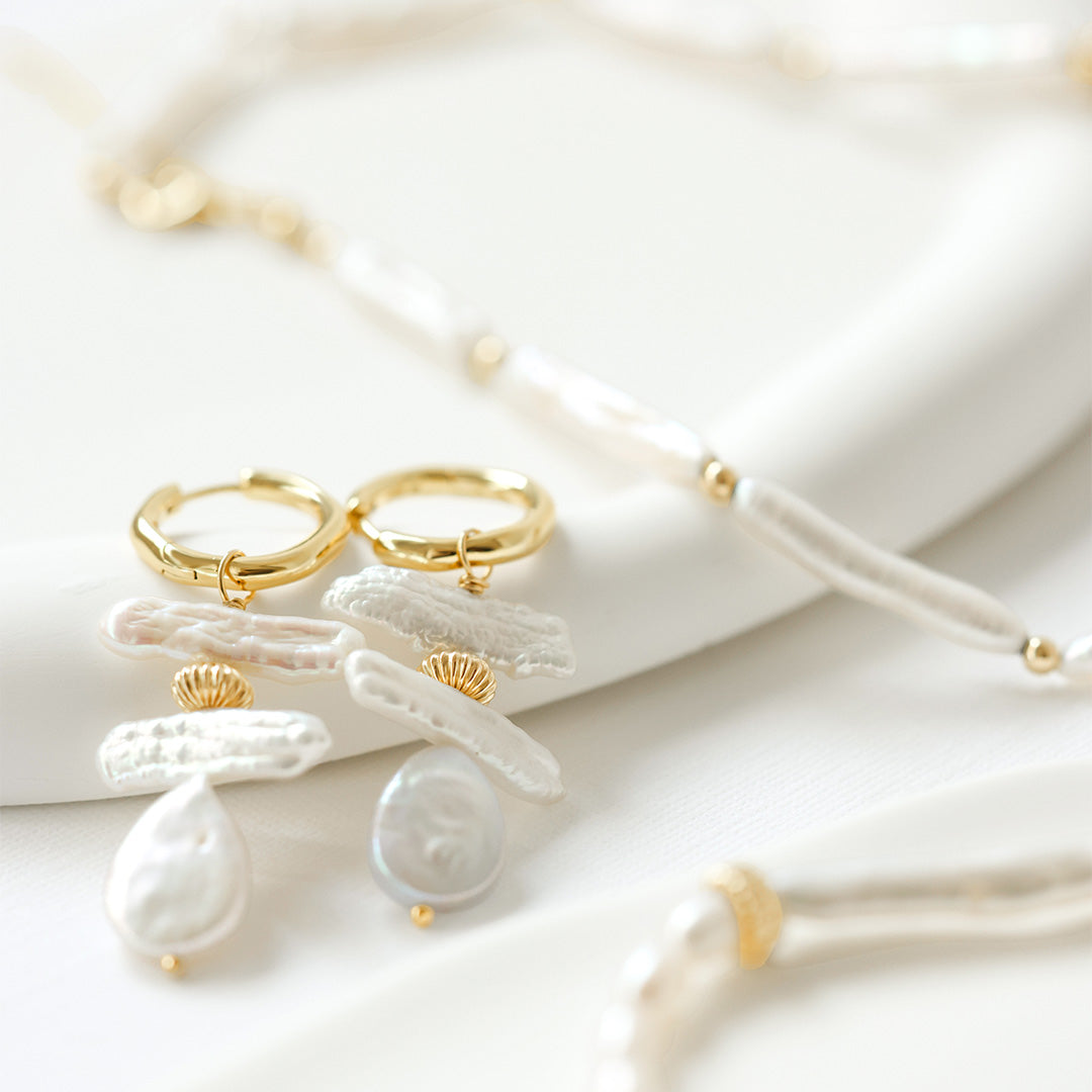 Gold and white jewelry set on a light background