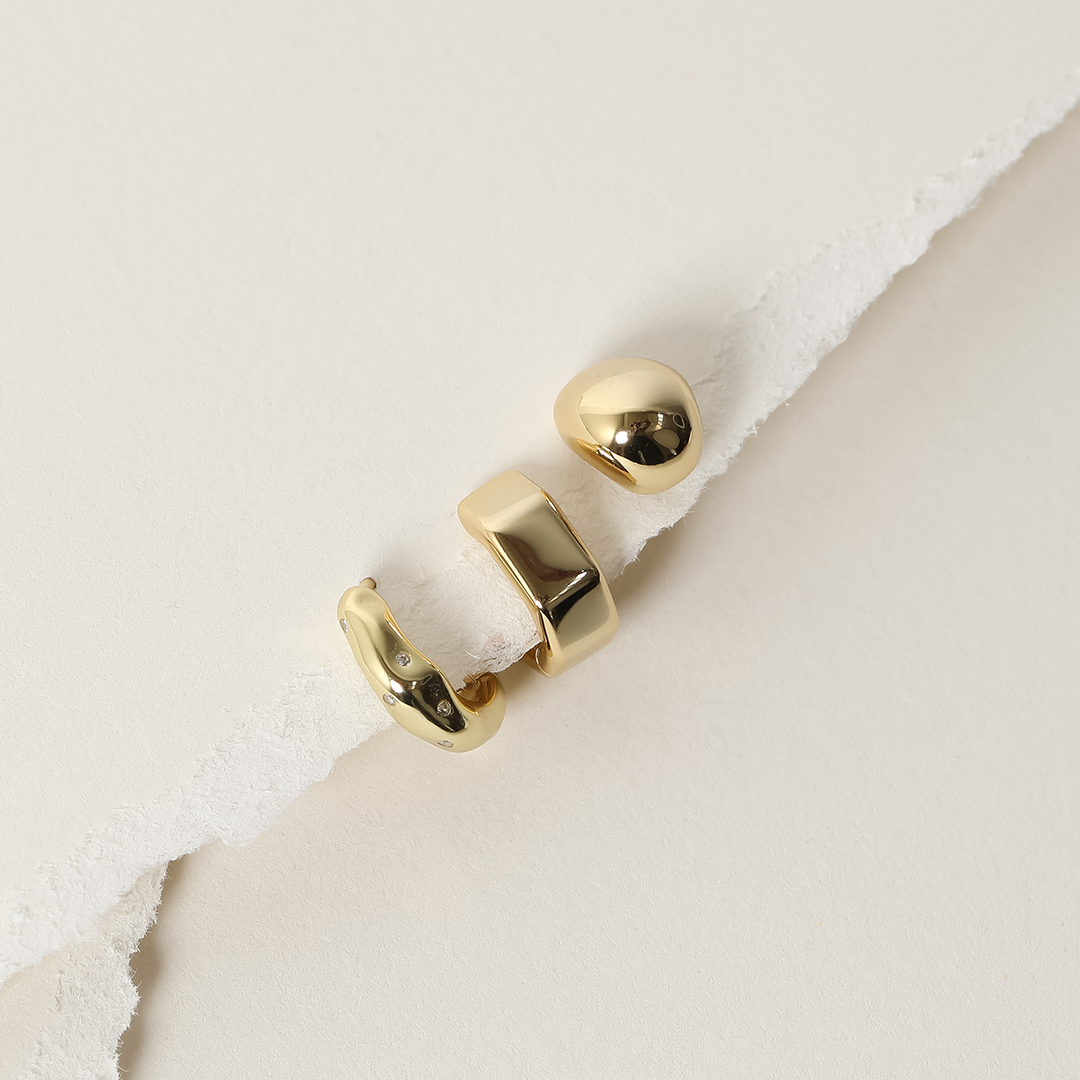 A pair of chunky bulb-shaped earrings in gold on white background next to gold earrings