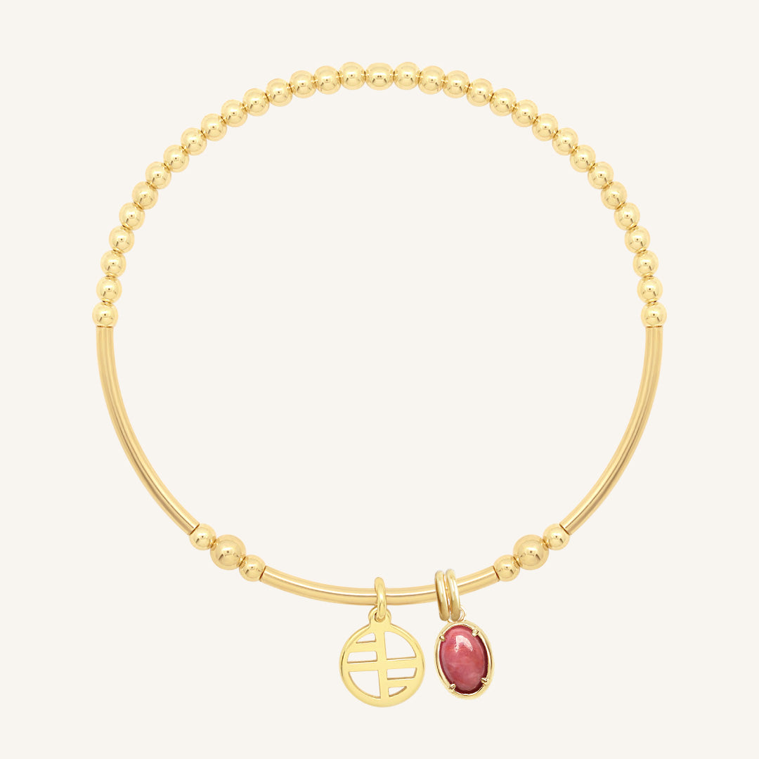 Gold bracelet with a pink charm on a white background