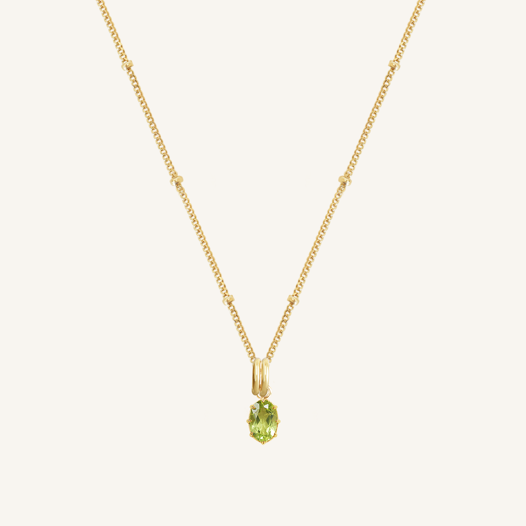 A green, oval-shaped charm pendant necklace with a gold metal chain.