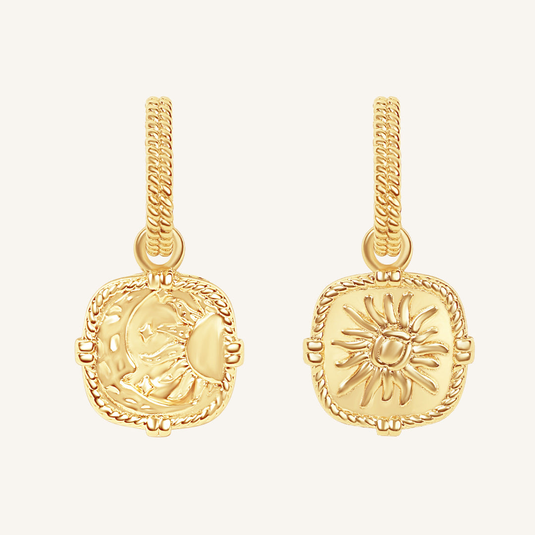 Pair of gold earrings with intricate designs on a white background