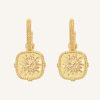 Gold earrings with sun design on a white background