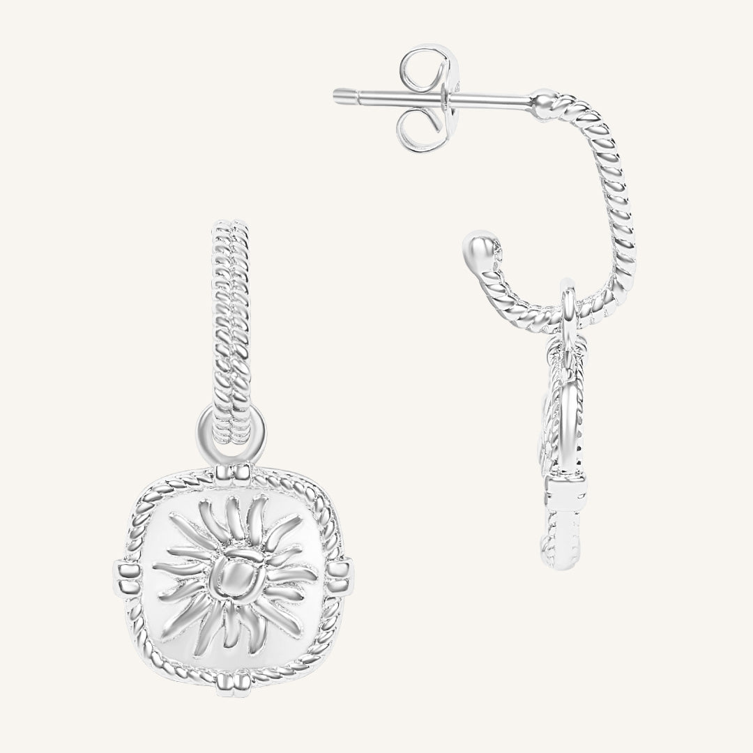 Silver sun-shaped earring on a white background