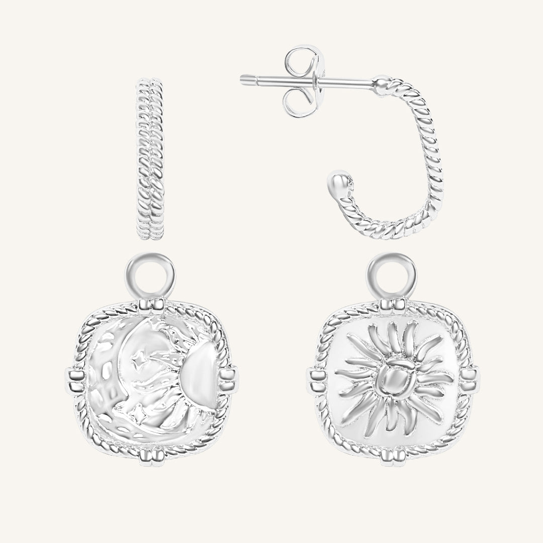 Silver earrings with sun and moon designs on a white background