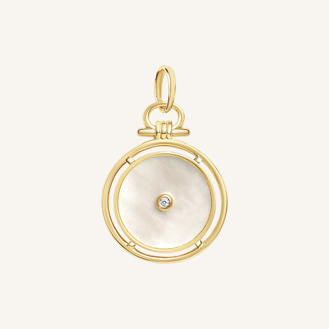 Gold pendant with a circular design and central gemstone on a light beige background