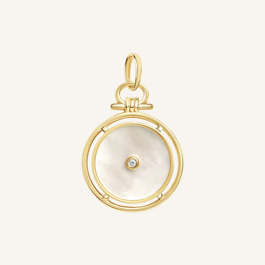 Gold pendant with a circular design and central gemstone on a light beige background