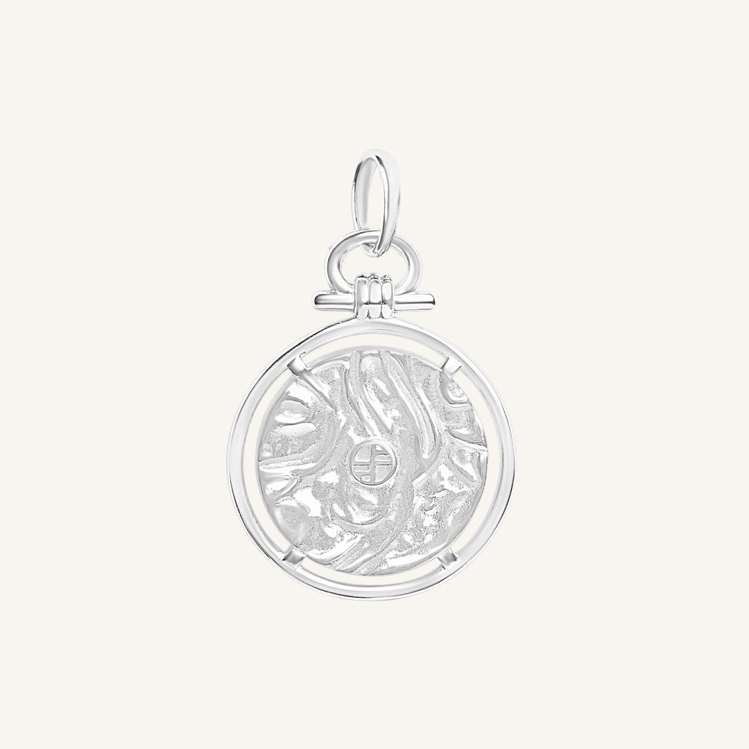 Silver pendant with intricate design on a white background