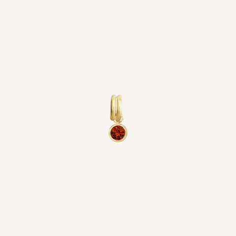 Round gold charm with bezel-set garnet cubic zirconia representing the January birthstone.
