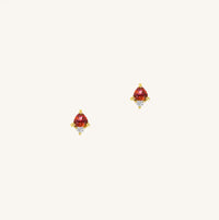 A gold pair of stud earrings featuring a red cubic zirconia, representing January.