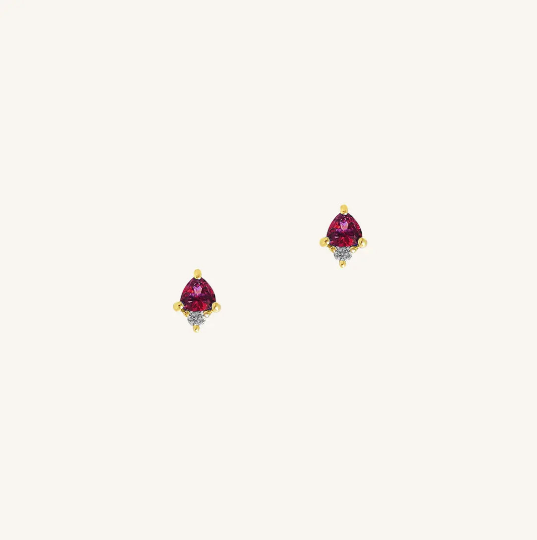 A gold pair of stud earrings featuring a red cubic zirconia, representing July.