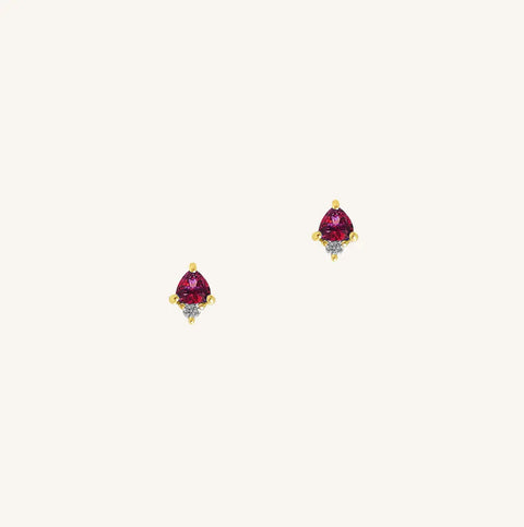 A gold pair of stud earrings featuring a red cubic zirconia, representing July.