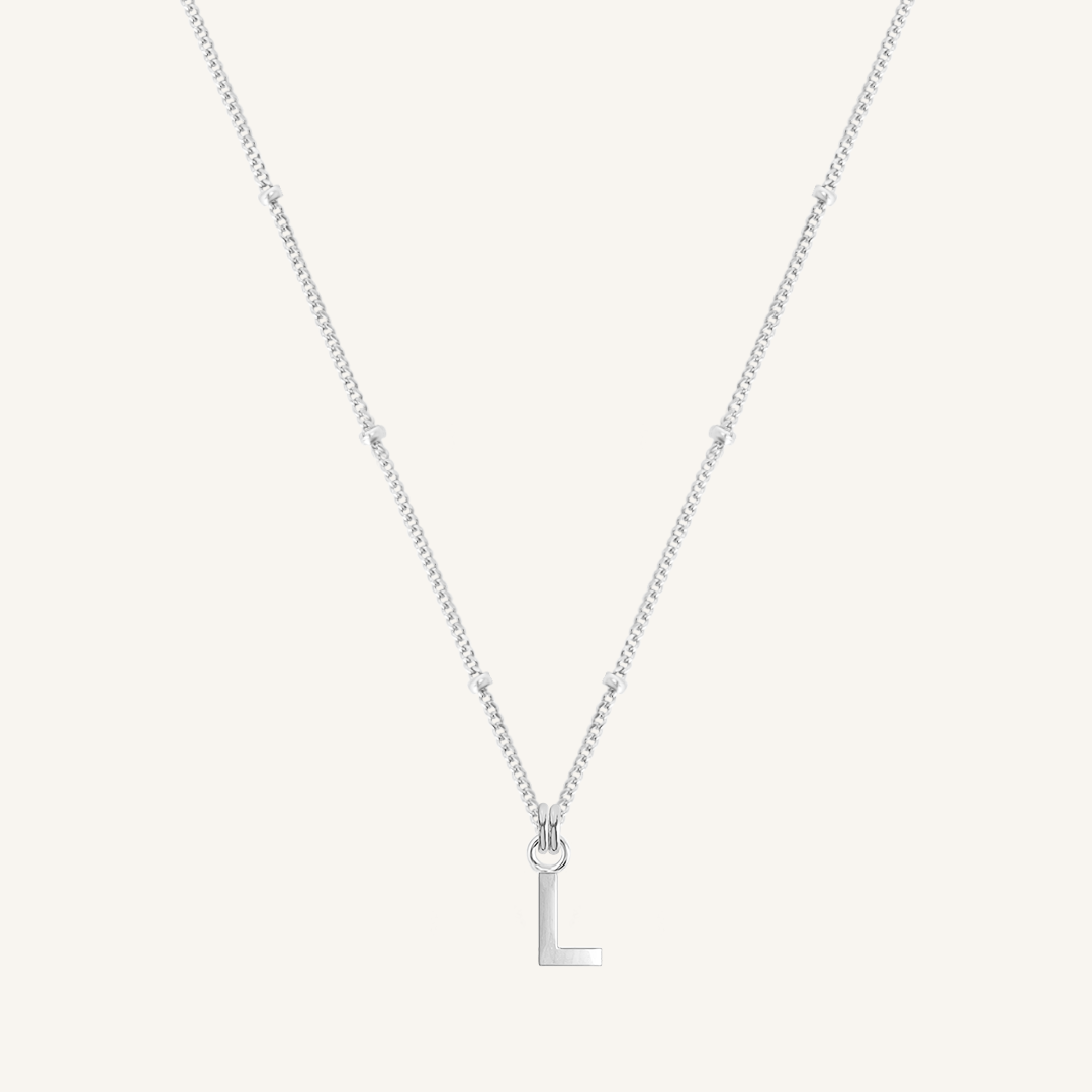 Silver necklace with a 'L' pendant on a light gray background