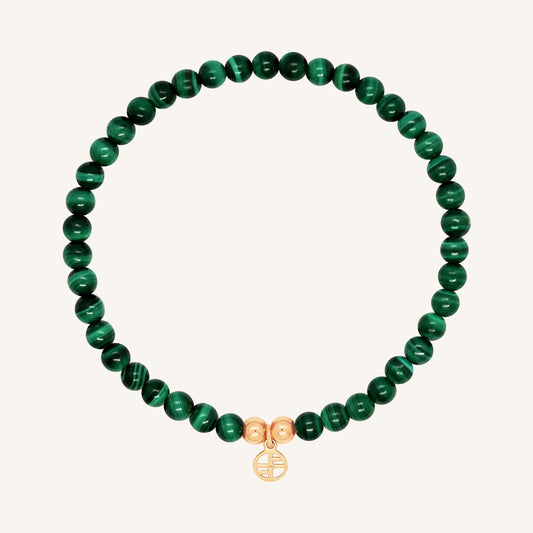 A beaded bracelet made of green malachite stones and metal beads with a rose-colored charm, displayed on a white background.