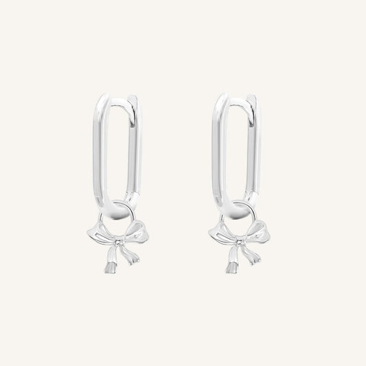 A pair of silver-tone charm hoop earrings with a simple bow design.