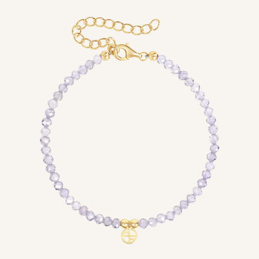Bracelet with light purple beads and gold clasp on a white background