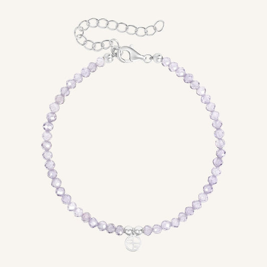 Silver bracelet with light purple beads on a white background