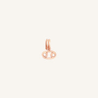 A small rose gold charm with the symbol for the zodiac sign Cancer.