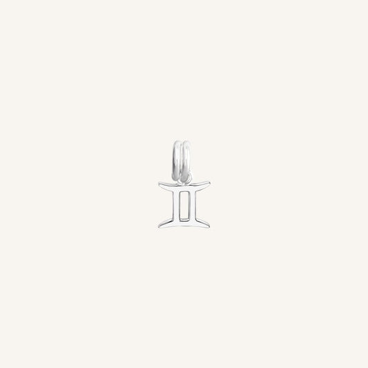 A silver charm representing the Gemini zodiac sign.