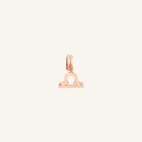 A rose gold charm in the shape of the Libra zodiac symbol.