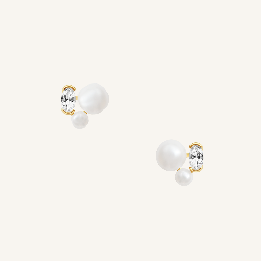 A pair of pearl stud earrings with gold accents on a white background.