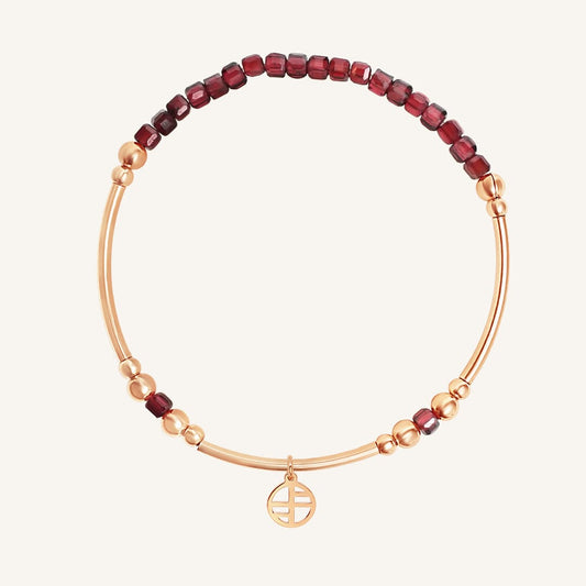 Bracelet with red beads and gold accents on a white background