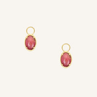 Gold hoop charms with pink gemstones on a white background