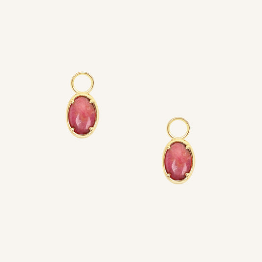 Gold hoop charms with pink gemstones on a white background