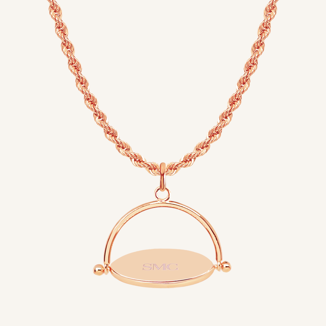 A rose-coloured, engraved pendant with, featuring a spinning mechanism, on chain