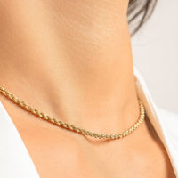 A silver rope chain necklace on a plain background.