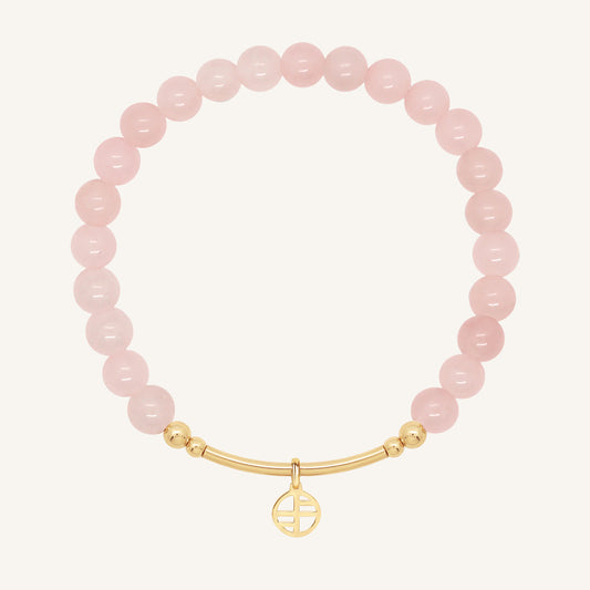 Pink beaded bracelet with a gold charm on a white background