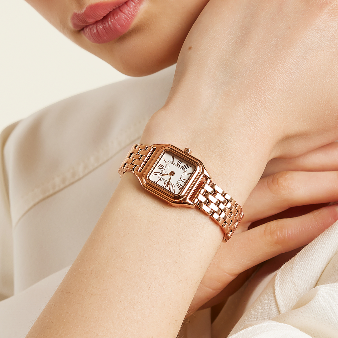 A rose gold-toned Louis Watch with a link bracelet and a square face featuring Roman numerals worn on the wrist