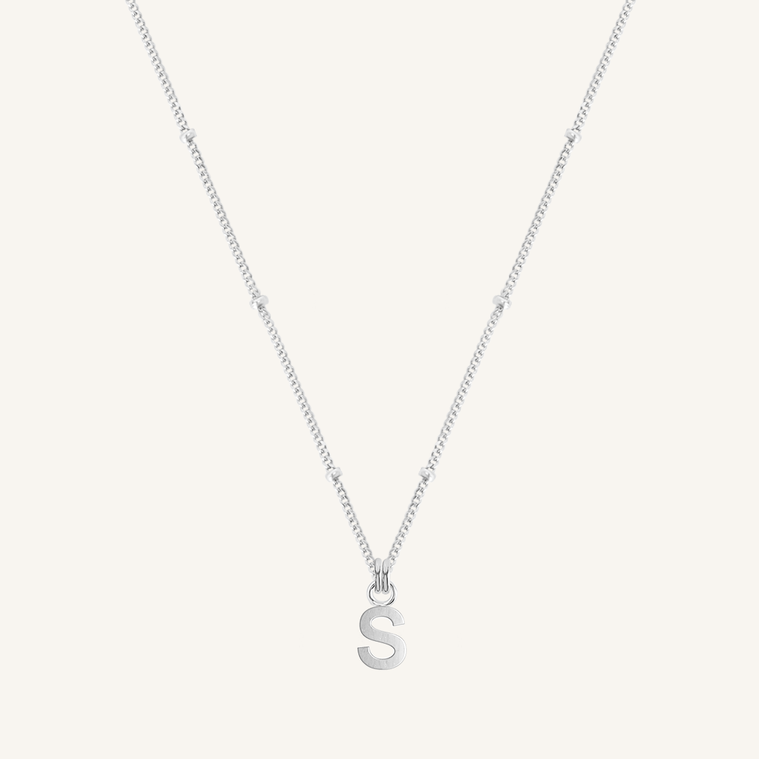 Silver necklace with a 'S' pendant on a light gray background