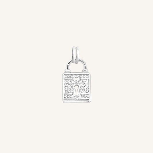 A silver-colored charm in the shape of a keylock with intricate patterns.