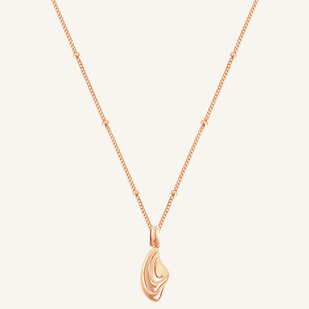 Rose gold necklace with a unique pendant on a light beige background