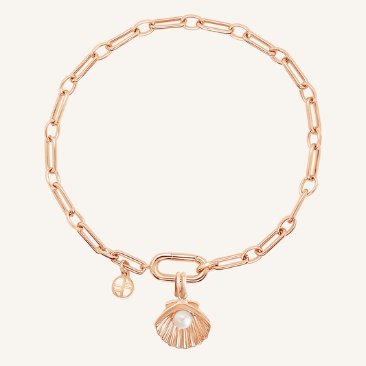 A rose-colored chain bracelet with a shell shaped charm with a pearl in the middle