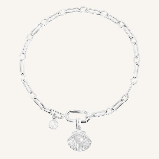 A silver-colored chain bracelet with a shell shaped charm with a pearl in the middle