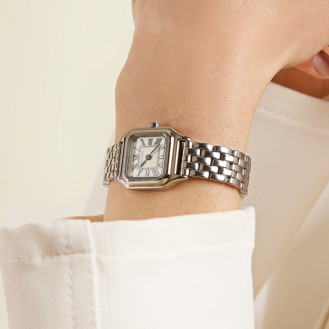 A silver-toned Louis Watch with a link bracelet and a square face featuring Roman numerals worn on the wrist