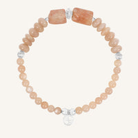 Bracelet with peach-colored beads and silver accents on a white background