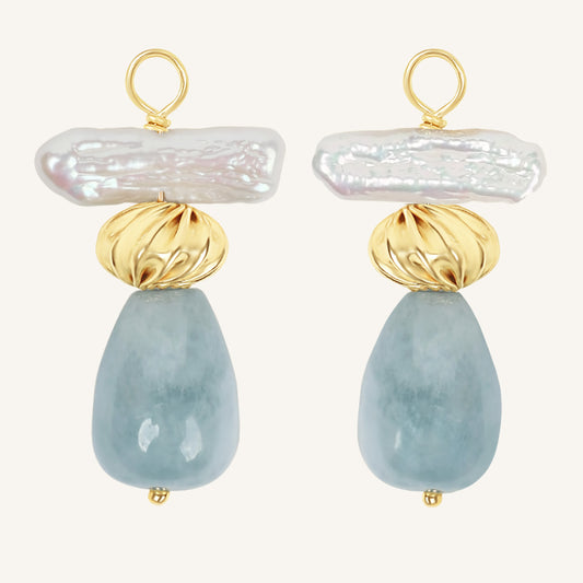 Pair of hoop charms with gold, pearl, and light blue stone design on a white background